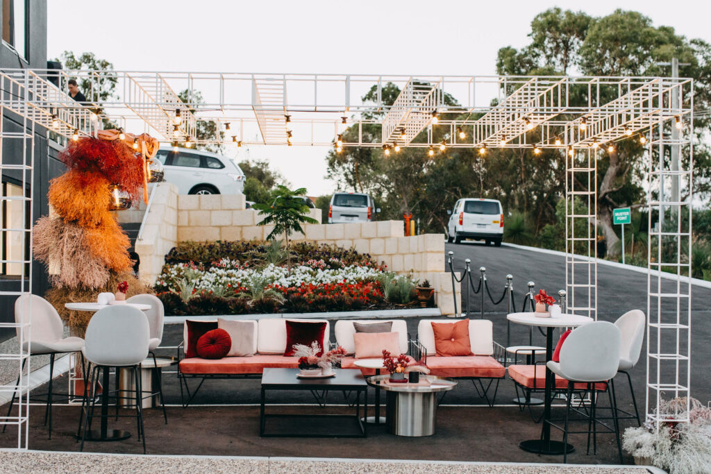 Corporate event styling for the event entrance featuring festoon lights, white chairs and amber flower installation