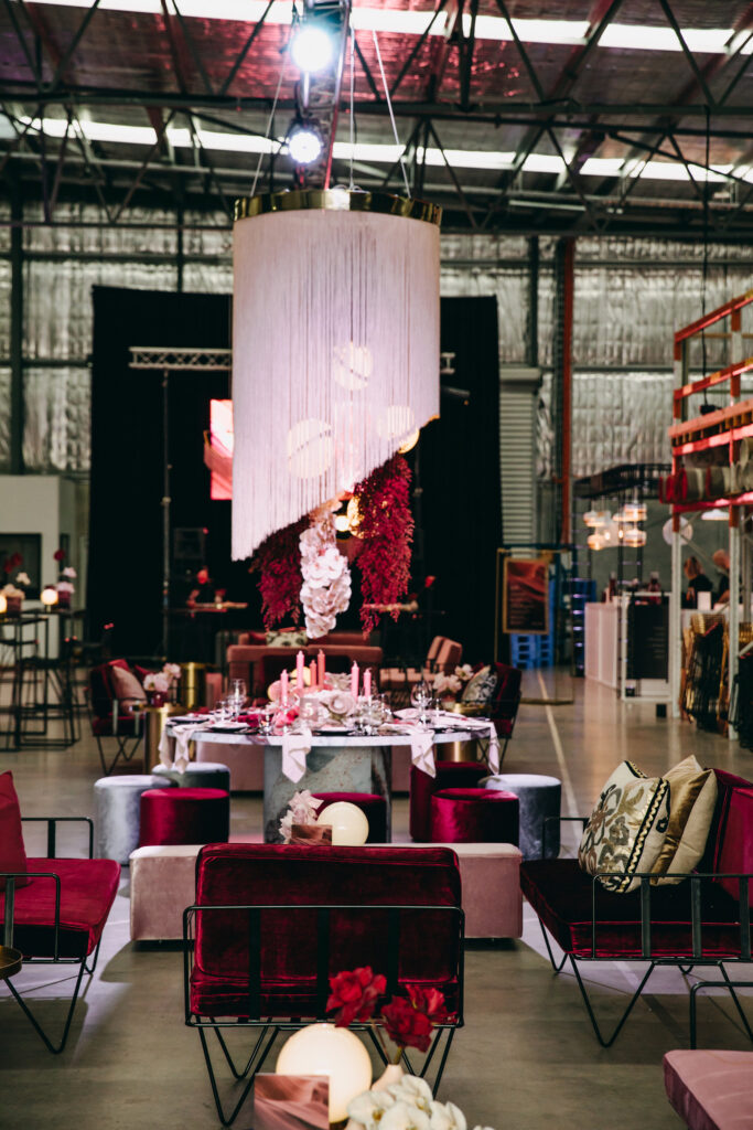 Corporate event styling including red velvet chairs, and pink fringed centrepiece
